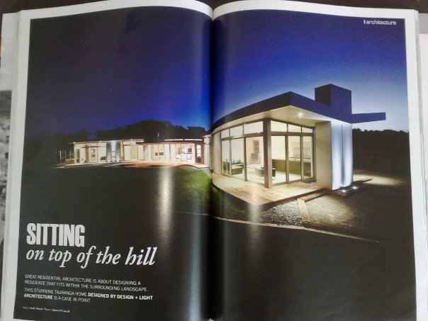 Magazine spread headlined 'Sitting on top of the hill' showing the Tauranga hillside residence at dusk