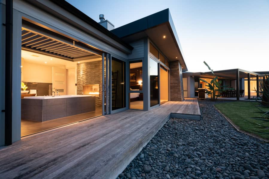 New Zealand home at dusk with timber deck and landscaped garden