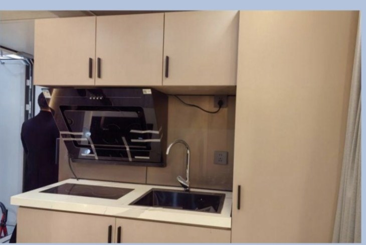 Compact cabin kitchen with pale cabinetry, induction cooktop and extraction hood
